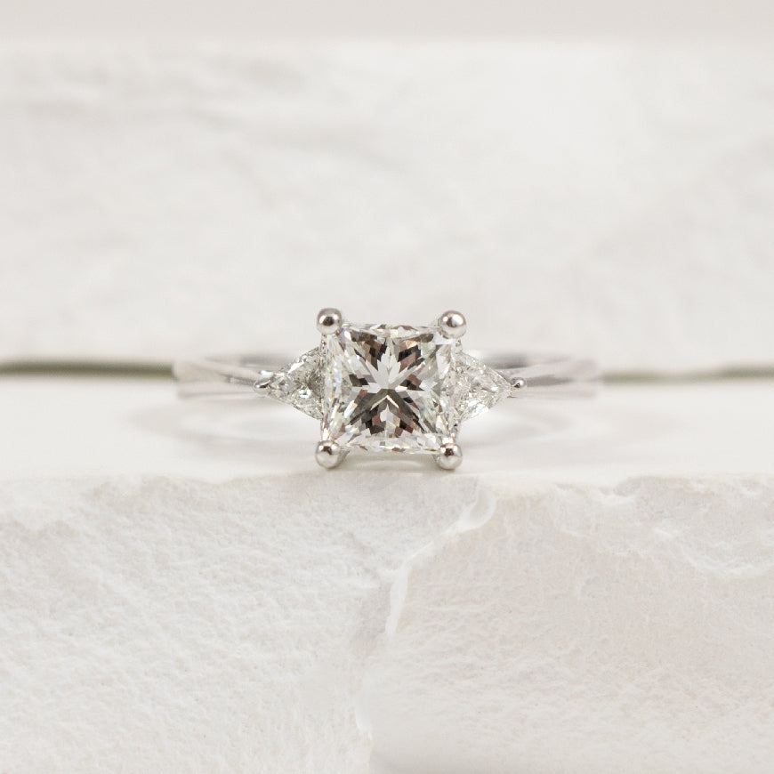 14KW EG Design Trinity Diamond Engagement Ring    
14K White Gold Natural Diamond Three Stone Engagement Ring  
Center Diamond - 1.02 Carat Princess Cut Natural Diamond of 
VS2 Clarity G-H Colour, Very Good Cut 
Accent Diamonds - 0.15 Carat