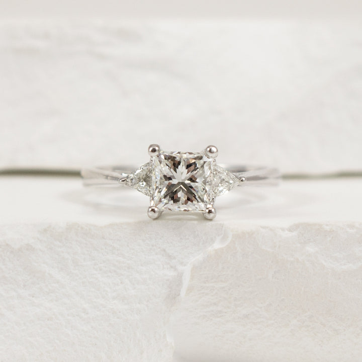14KW EG Design Trinity Diamond Engagement Ring    
14K White Gold Natural Diamond Three Stone Engagement Ring  
Center Diamond - 1.02 Carat Princess Cut Natural Diamond of 
VS2 Clarity G-H Colour, Very Good Cut 
Accent Diamonds - 0.15 Carat