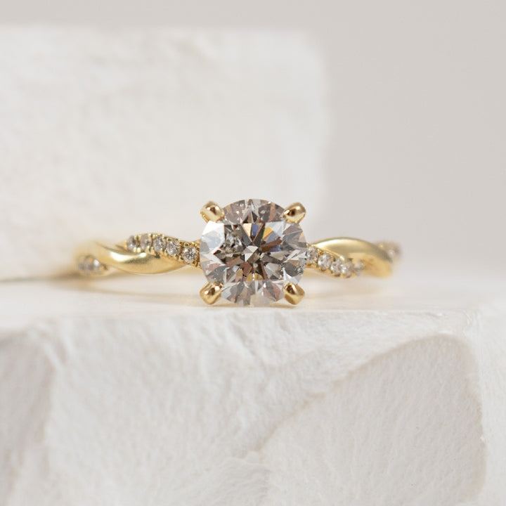 14K Yellow Gold Roman & Jules Canadian Natural Diamond Twist Engagement Ring 
Center - 1.01 Carat Round Brilliant Cut Canadian Natural Diamond of I1 Clarity, G Colour, Very Good Cut 
Accent - 0.08 Carats Round Brilliant Cut Natural Diamonds of