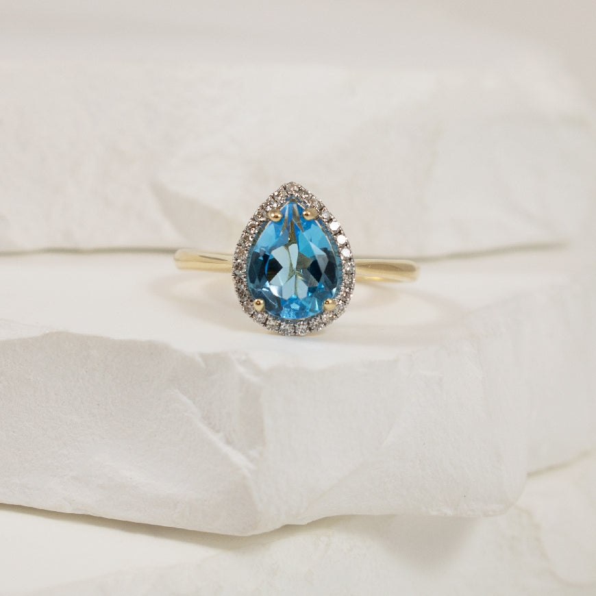 10KY Pear Shaped Blue Topaz & Diamond Halo Ring    
10K Yellow Gold Blue Topaz & Natural Diamond Ring
0.135 Total Natural Diamond Weight
Finger Size 7