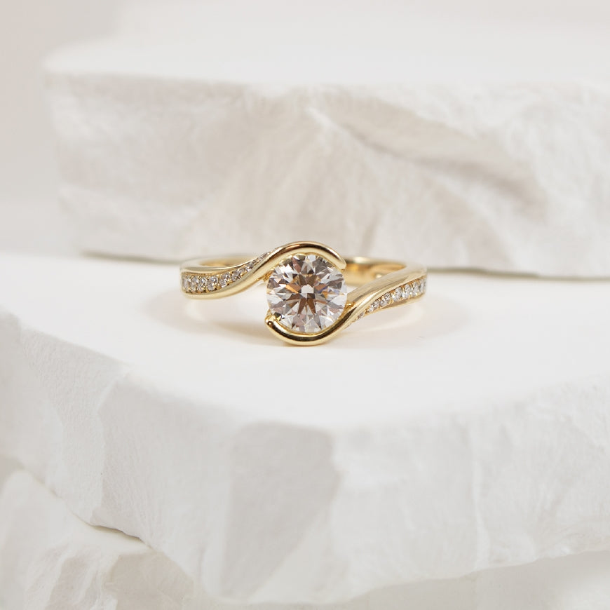 14KY 1.00CT Twisted Bezel Diamond Engagement Ring
14K Yellow Gold Roman & Jules Lab Grown & Natural Diamond Twist Engagement Ring 
Center - 1.00CT Round Brilliant Cut Lab Grown Diamond VS+ Clarity, GHI Colour, Very Good Cut
Accent - 0.22 Car