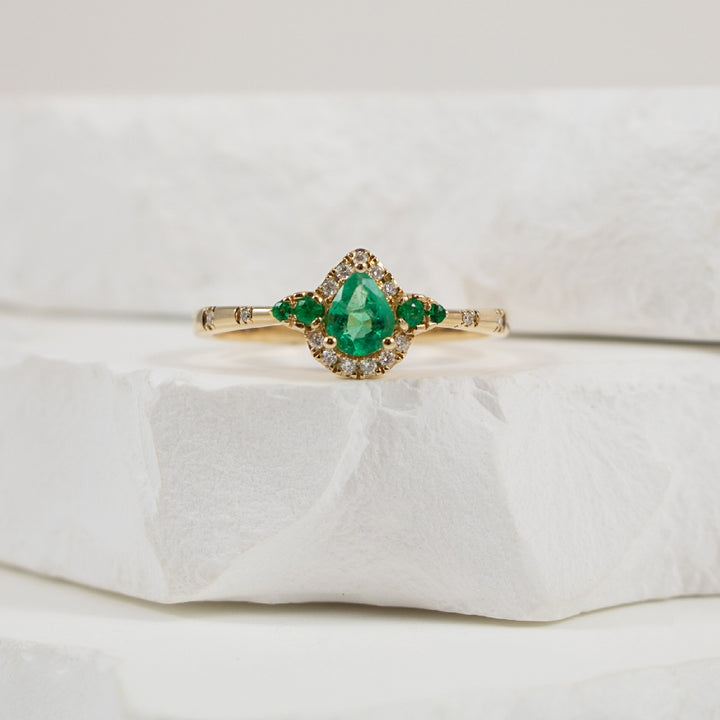 14KY Bassali Emerald & Diamond Halo Ring          
14K Yellow Gold Bassali Pear Shaped Emerald & Diamond Halo Ring 
0.40 Total Emerald Weight 
0.06 Total Natural Diamond Weight SI1-2 Clarity, GH Colour
Finger Size