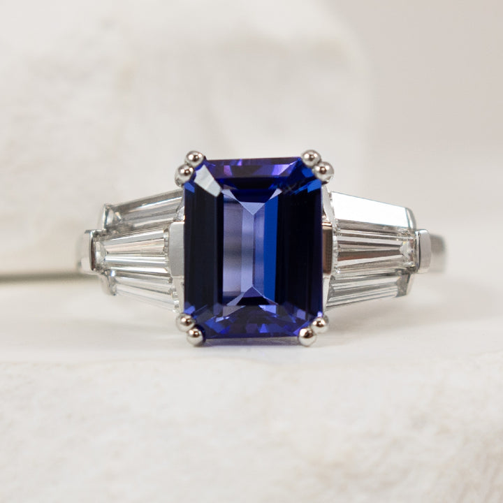 Platinum Emerald Cut Tanzanite & Diamond Ring 

Platinum Natural Emerald Cut Tanzanite & Taper Baquette Cut Diamond Ring

2.58 Carat of Natural Emerald Cut Tanzanite of Medium Dark Tone, Vivid Saturation, Violetish Blue Hue, Loupe Clean, Excellen