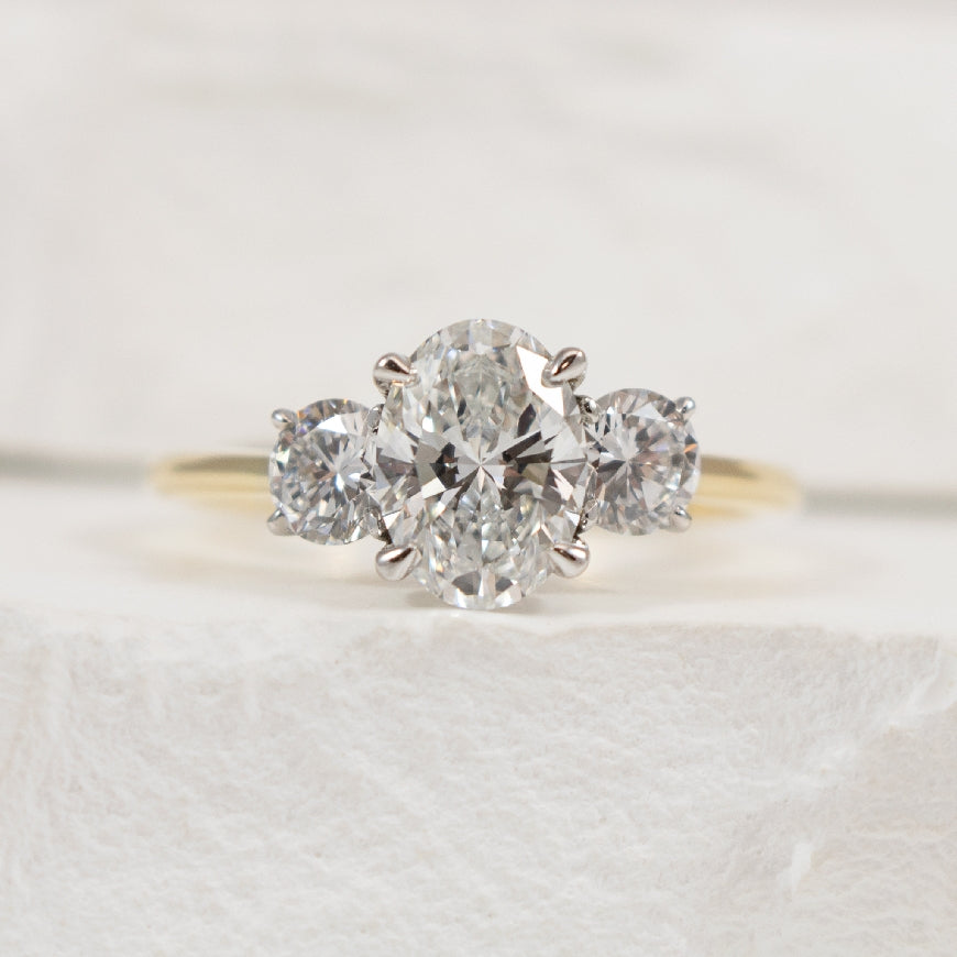 14KY Oval Cut Trinity Diamond Engagement Ring   

14K Yellow & White Gold Oval Lab Grown Diamond Three Stone Engagement Ring 

Center - 1.00 Carat Oval Cut of VS2 Clarity, D Colour, Excellent Cut, IGI Certified 

Accent - 0.50 Carats Round Bril