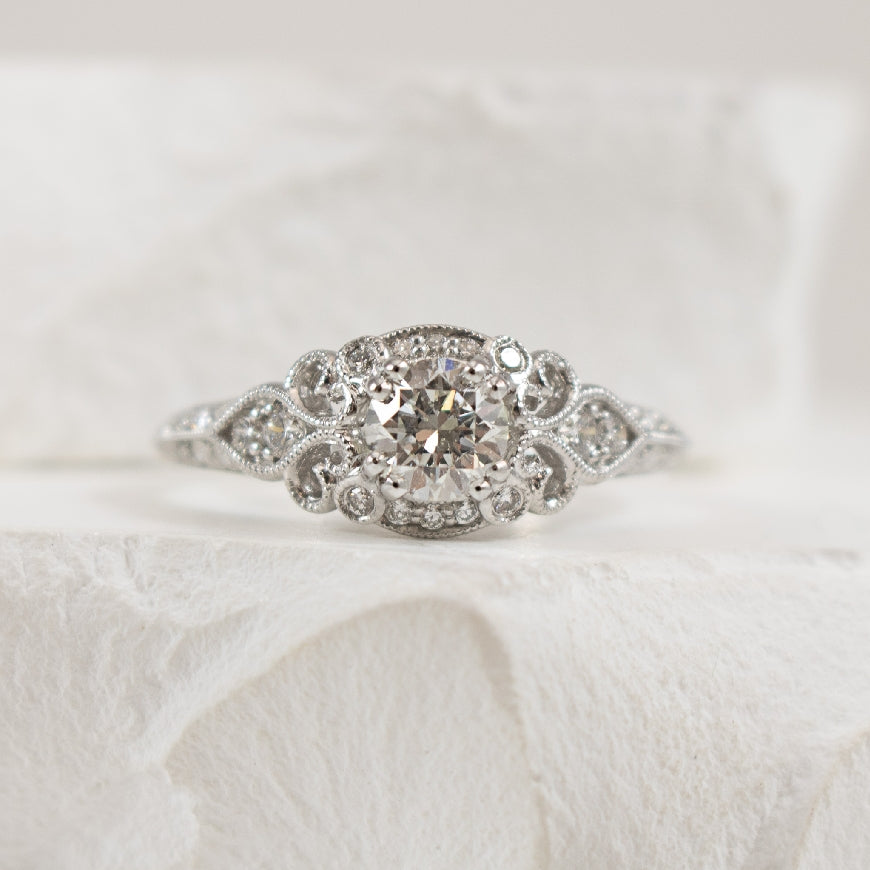 14K White Gold Gabriel & Co. Vintage-Style Natural Diamond Engagement Ring 

Center - 0.47 Carat Round Brilliant Cut Natural Diamond of I1 Clarity, G Colour 

Accent - 0.30 Carats Natural Diamonds SI2+ Clarity, GH Colour 

0.77 Total Diamond We