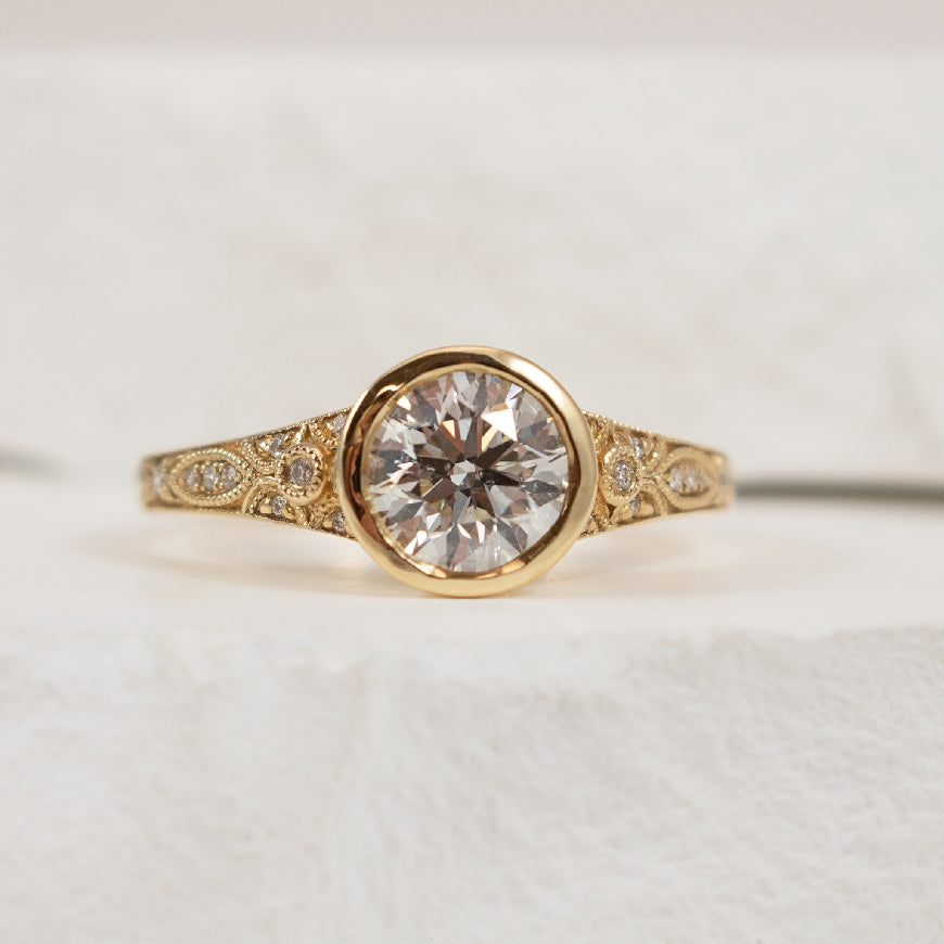 14KY Vintage Style Bezel Diamond Engagement Ring 

14K Yellow Gold Natural Diamond Accented Engagement Ring  

Center - 1.00CT Round Brilliant Cut Natural Diamond of SI2 Clarity, I Colour, Excellent/ Excellent/ Excellent Cut 

Accent - 0.05 Car