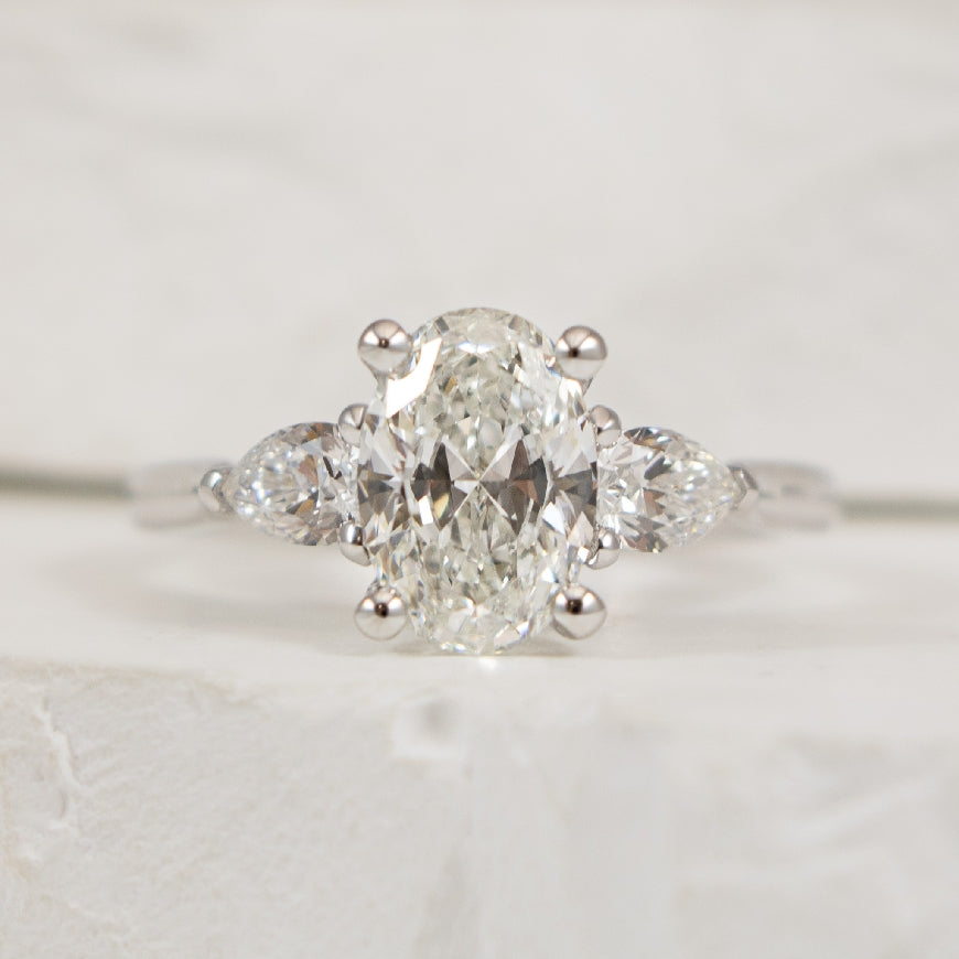 14KW 1.50CT Oval Trinity Diamond Engagement Ring  

14K White Gold Gabriel & Co. Oval Cut & Pear Shaped Three Stone Natural Diamond Engagement Ring 

Center - 1.50CT Oval Cut Natural Diamond of SI1 Clarity,  G Colour, Excellent Cut 

Accent - 0