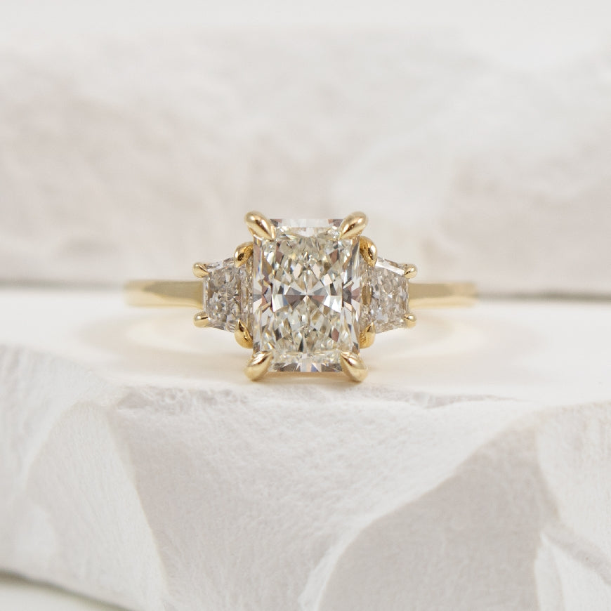 14KY Radiant & Trapezoid Diamond Engagement Ring  

14K Yellow Gold Radiant & Trapezoid Cut Three Stone Lab Grown Diamond Engagement Ring

Center - 1.55CT Radiant Cut VS1 Clarity, F Colour, Excellent/ Excellent Cut 

Accent - 0.44 Carats Trapez