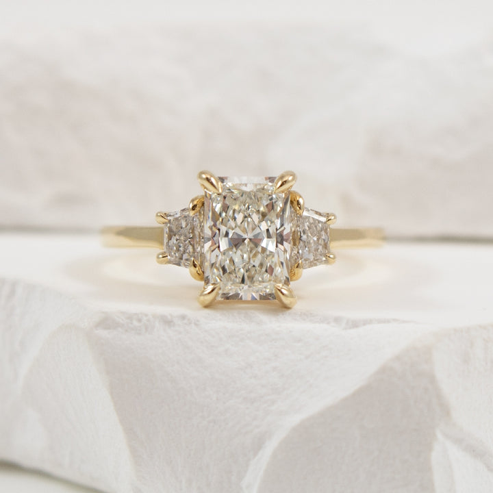 14KY Radiant & Trapezoid Diamond Engagement Ring  

14K Yellow Gold Radiant & Trapezoid Cut Three Stone Lab Grown Diamond Engagement Ring

Center - 1.55CT Radiant Cut VS1 Clarity, F Colour, Excellent/ Excellent Cut 

Accent - 0.44 Carats Trapez