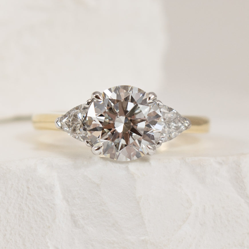 14K 2.52CT Trinity Diamond Engagement Ring        

14K Yellow & White Gold Round Brilliant & Trillion Cut Lab Grown Diamond Three Stone Engagement Ring 

Center - 2.02 Carat Round Brilliant Cut of VVS2 Clarity, E Colour, Ideal Cut, IGI Certified