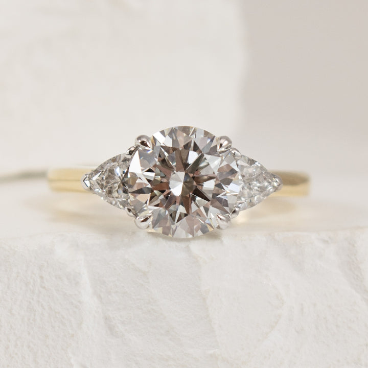 14K 2.52CT Trinity Diamond Engagement Ring        

14K Yellow & White Gold Round Brilliant & Trillion Cut Lab Grown Diamond Three Stone Engagement Ring 

Center - 2.02 Carat Round Brilliant Cut of VVS2 Clarity, E Colour, Ideal Cut, IGI Certified