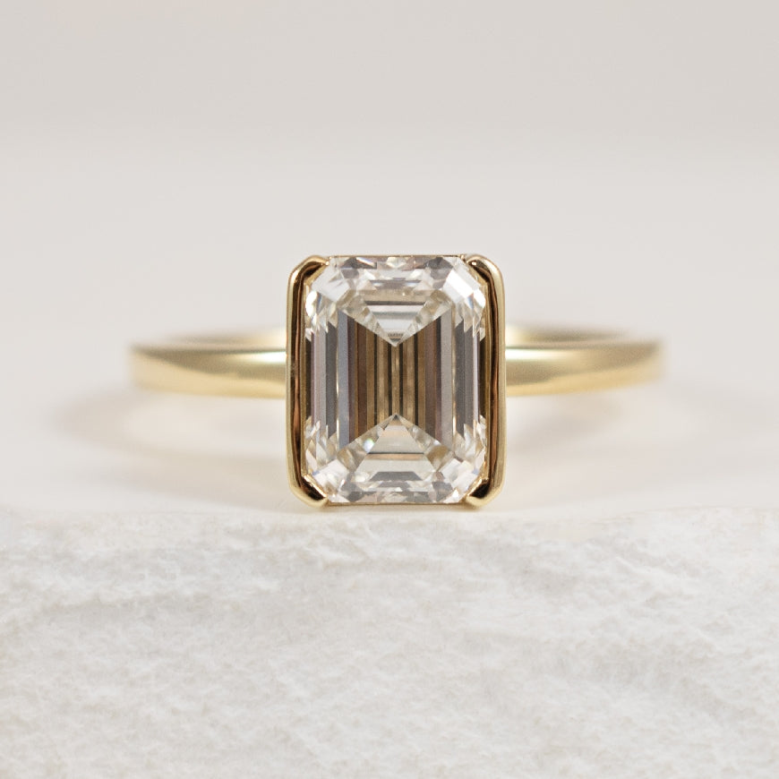 14K Yellow Gold Half Bezel Set Emerald Cut Lab Grown Diamond  Engagement Ring 

2.08 Carat of Lab Grown Emerald Cut Diamond of VVS2 Clarity, E Colour, Excellent/Excellent/Excellent Cut, IGI Certified 

2.17 Total Diamond Weight 

Finger Size 

