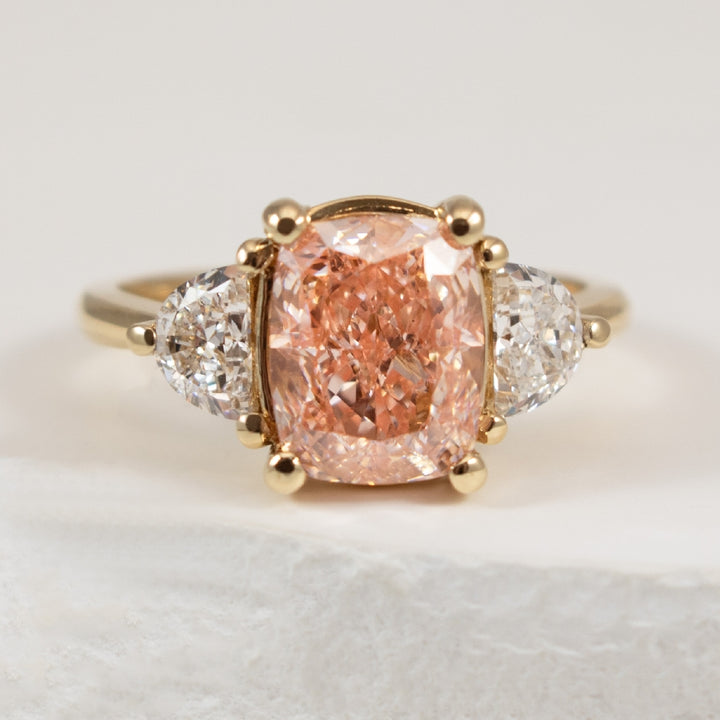 14K Yellow Gold Pink Diamond Three Stone Engagement Ring

Center - 3.00 Carat of Cushion Cut Lab Grown Pink Diamond, VS+ Clarity,

Accent - 0.60 Total Half Moon Shaped Lab Grown Diamond Weight of VS+ Clarity, F+ Colour
(0.30 Carat per Half Moon)